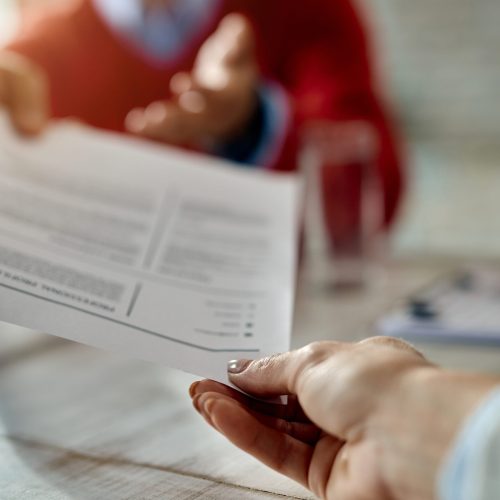 Close-up of job applicant giving his resume during job interview in the office.